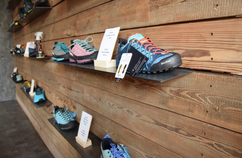 Regal mit Schuhen in verschiedenen Farben an einer Holzwand